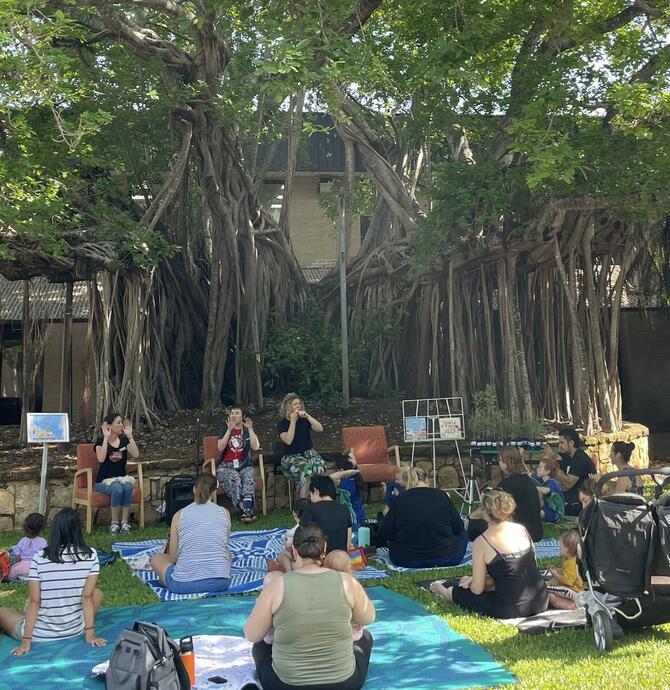 groups of families enjoying story time under the tree of knowledge