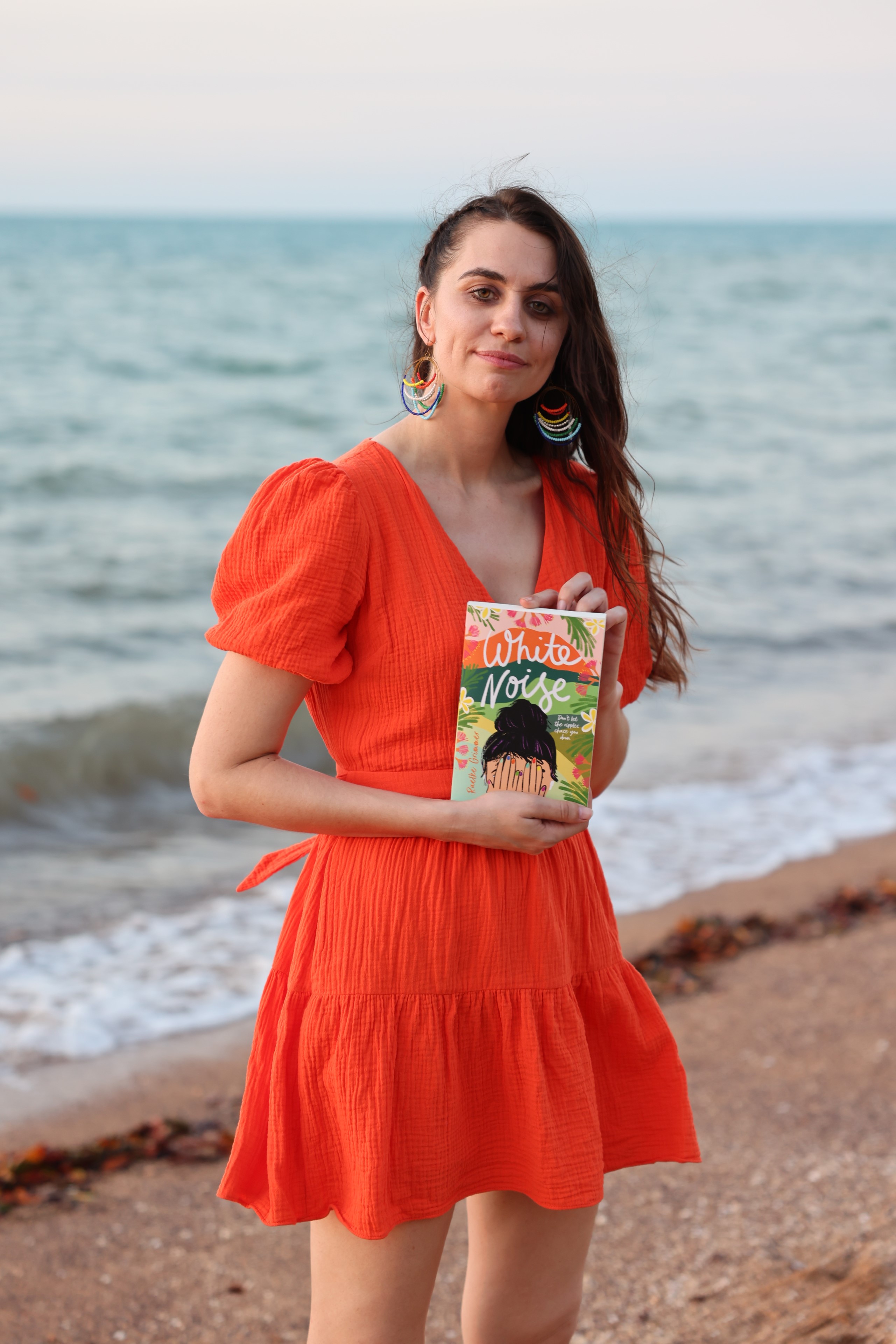 Author Raelke Grimmer holding her book White Noise 