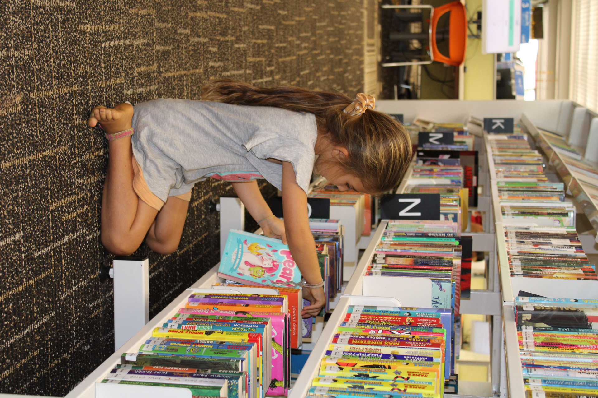 Girl picking a book from the shelf