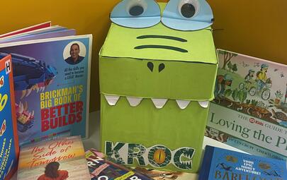 croc made from cardboard box surrounded by books