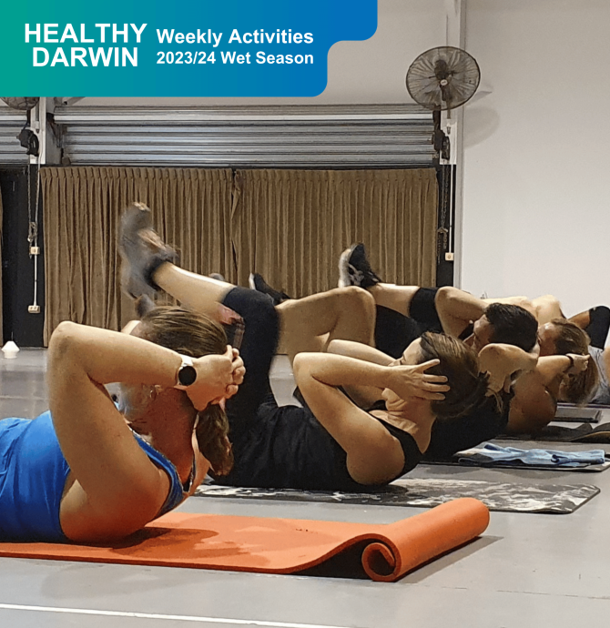 Group of people on the ground working out together on gym mats
