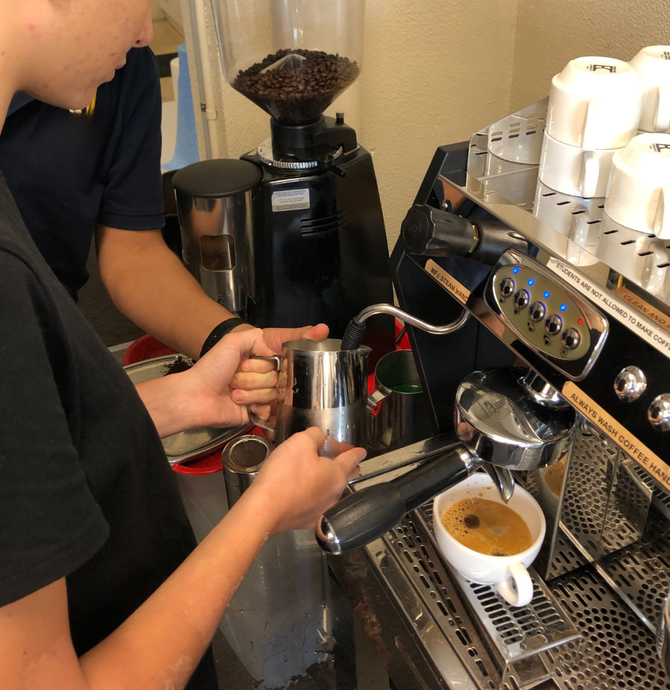 Person using coffee machine to froth milk 