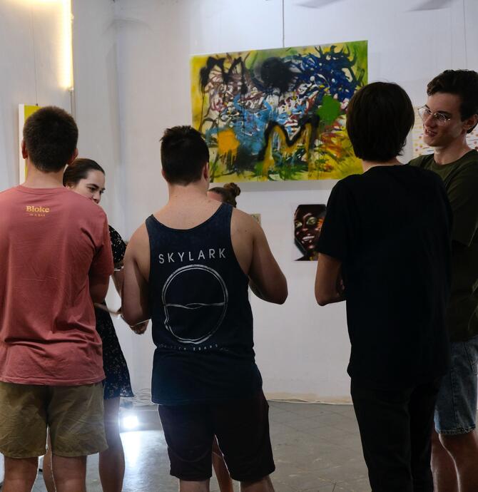group of young people standing in front of a piece of artwork, in conversation