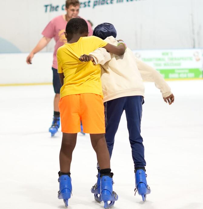two young people ice skating holding each other up for support