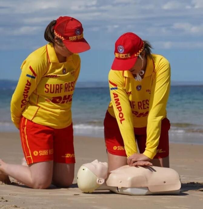 Surf lifesavers providing first aid on first aid dummy
