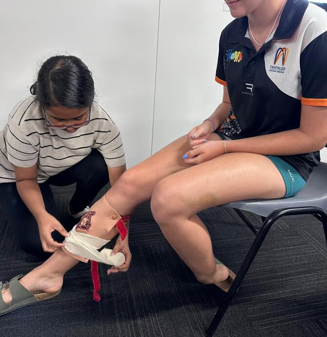two young people practicing first aid bandaging 