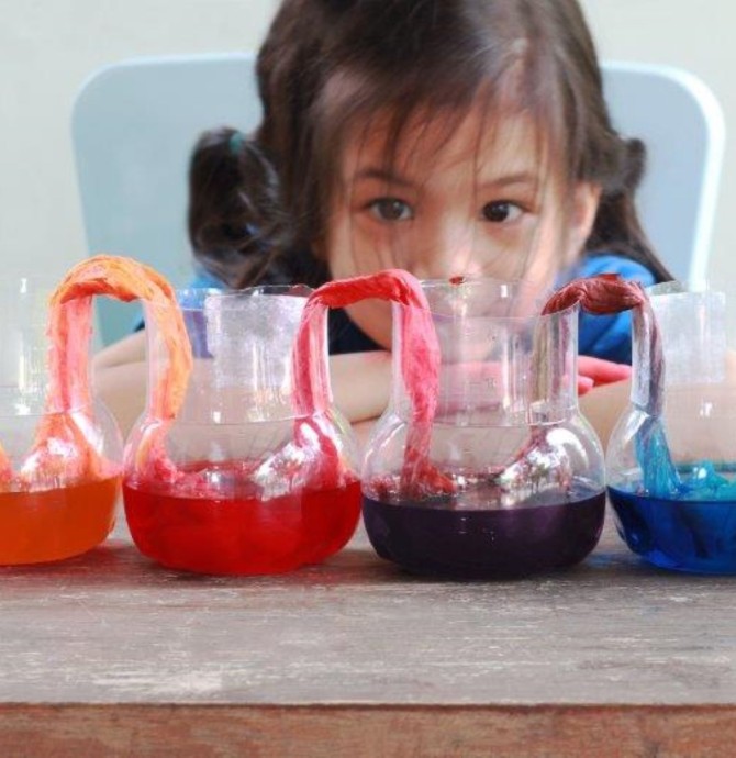 image of young girl looking a jars with colour water