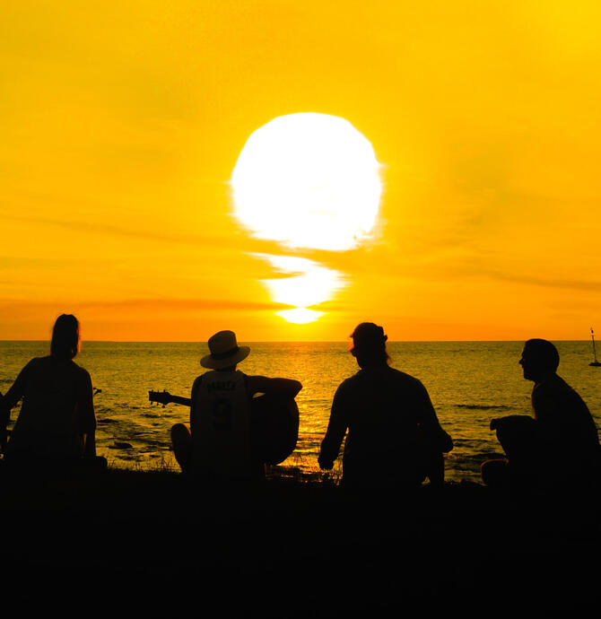 four young people and a dog watching the sunset