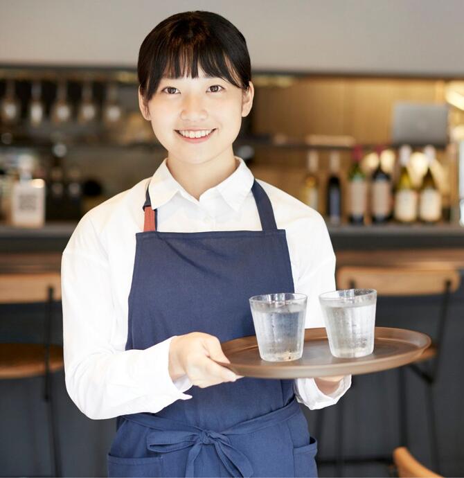 Young person holding glasses of water on serving tray