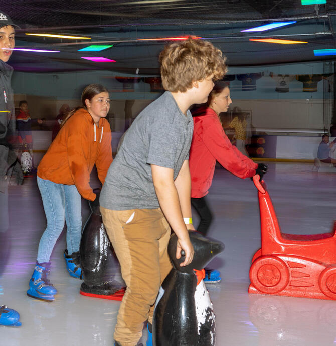 group of young people ice skating with support props