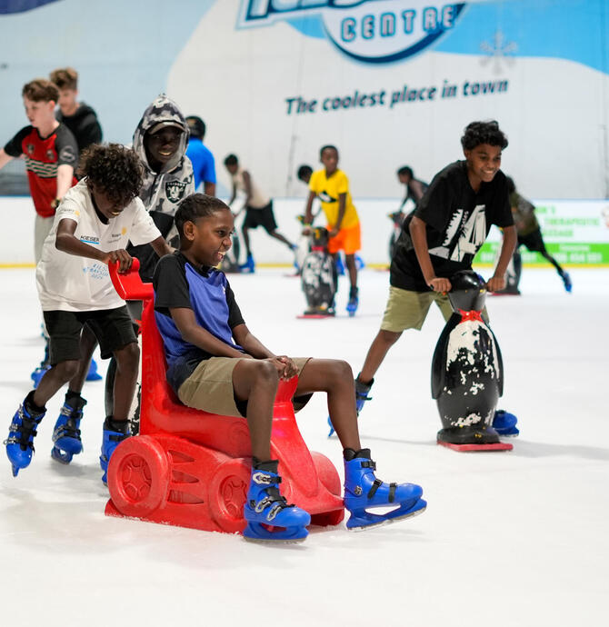 Young people ice skating and using skating aids