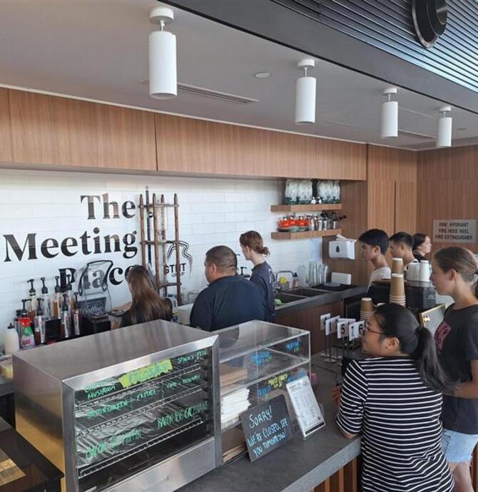 group of young people standing at counter, some making smoothies, others watching
