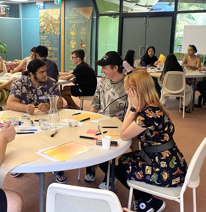 young people gathered around tables discussing ideas