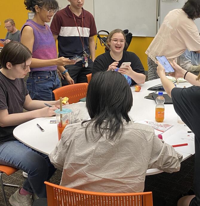 Young people sharing digital art around a table at the library
