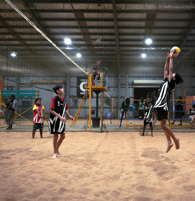 young people playing indoor beach volleyball