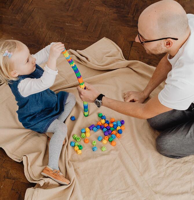 man and child playing with beads on mat