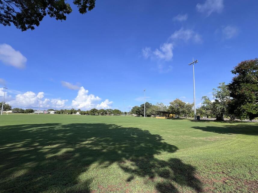 Ground level view of Bagot Oval, showing its four light towers, the original pavilion and the carpark behind